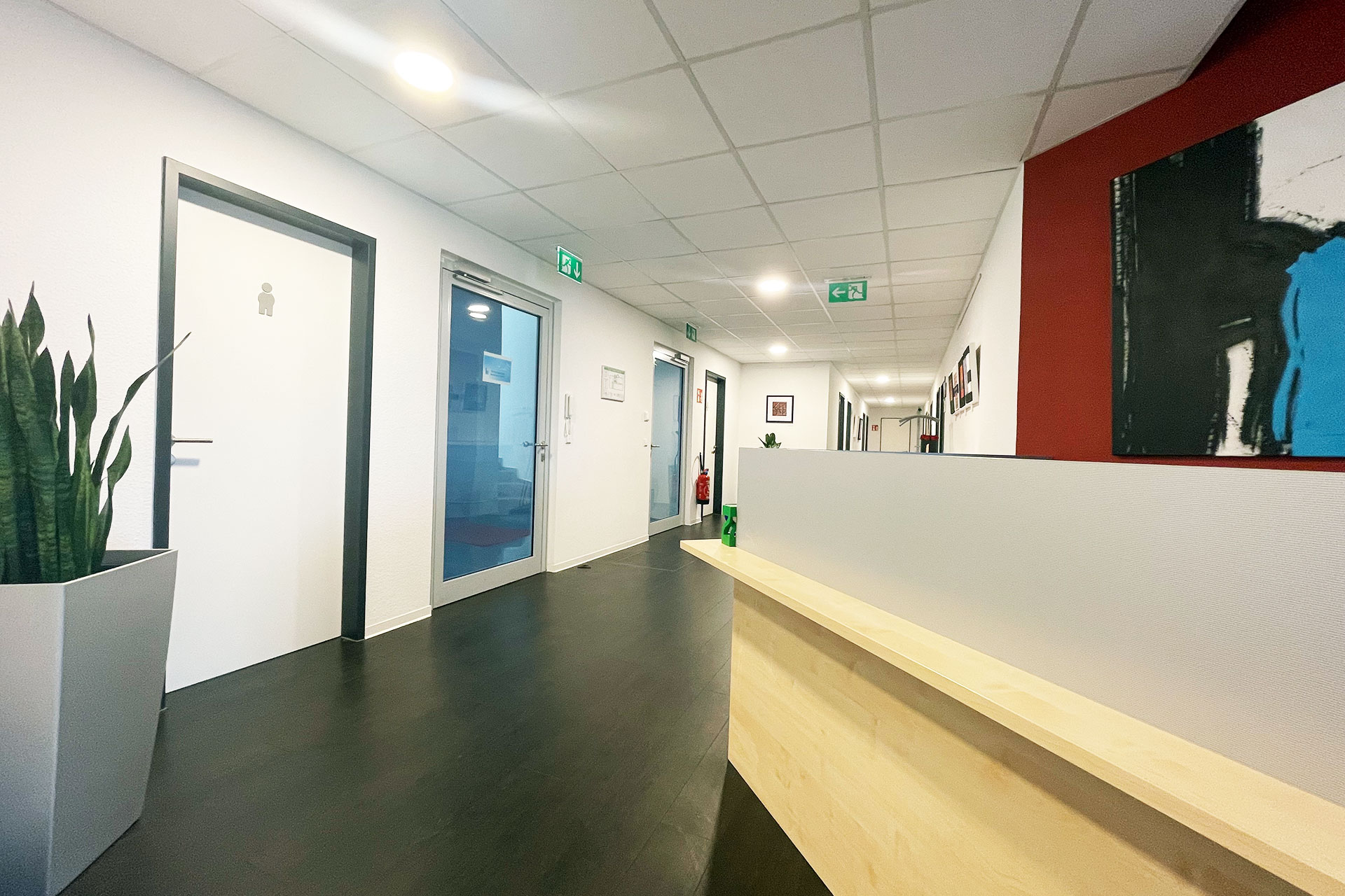 Moderner Büroflur mit Empfangstheke, Türen zu Büroräumen und heller Deckenbeleuchtung