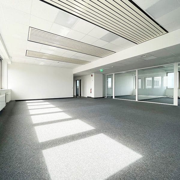 Großzügige, lichtdurchflutete Bürofläche mit großen Fenstern, Teppichboden, integrierten Glastrennwänden und moderner Deckenbeleuchtung