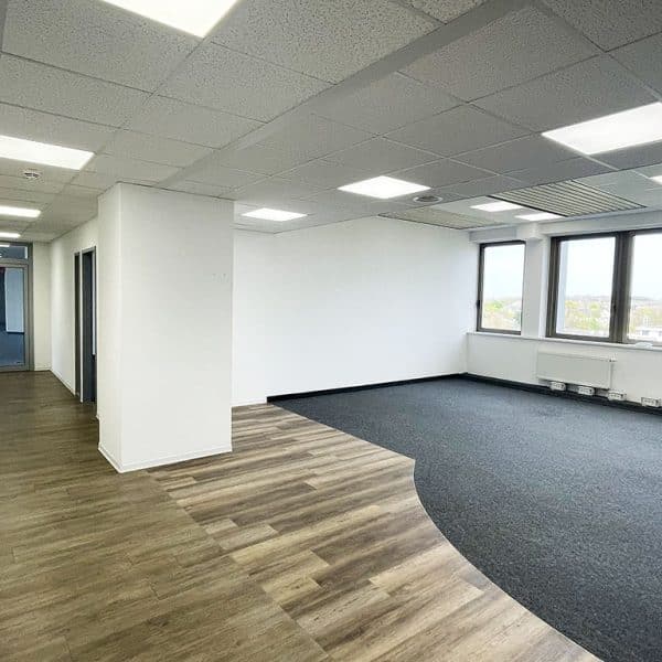 Moderner Büroraum mit viel Tageslicht, Deckenbeleuchtung und Zugang zu weiteren Räumen