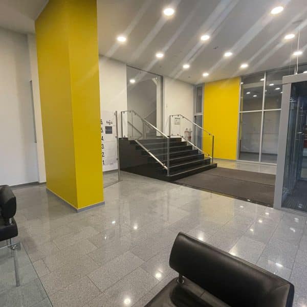 Modernes Büro-Foyer mit gelben Wänden, Treppe und Sitzbereich